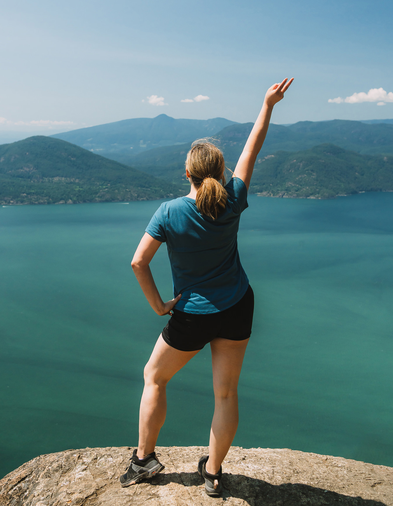 Hiker looking towards Howe Sound from Tunnel bluffs viewpoint with her hand up