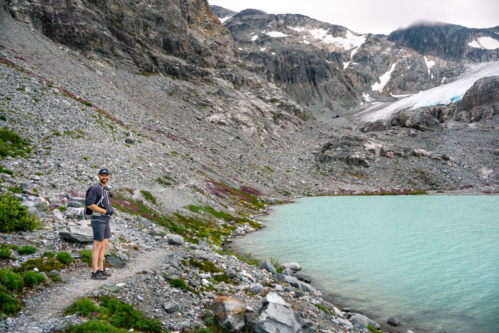 Smiling hiker standing by the glacial Wedgemount Lake