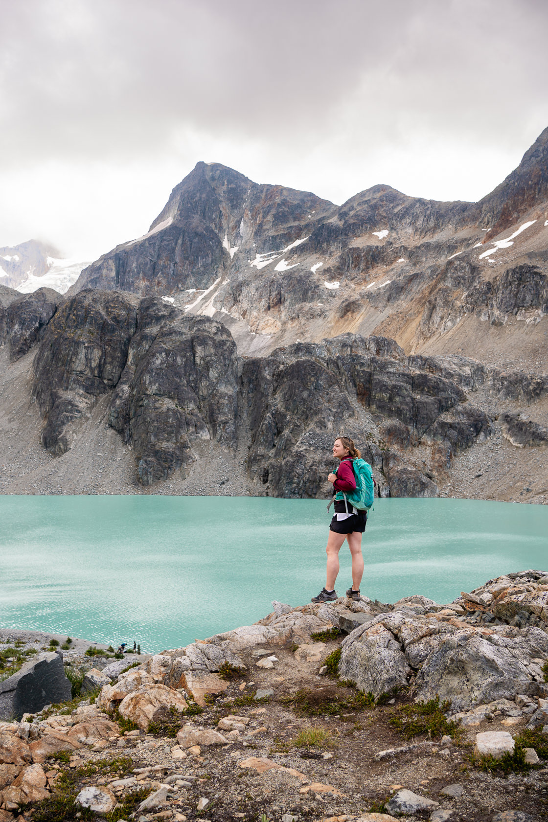 Hiker looking at the turquoise Wedgemount Lake while hiking