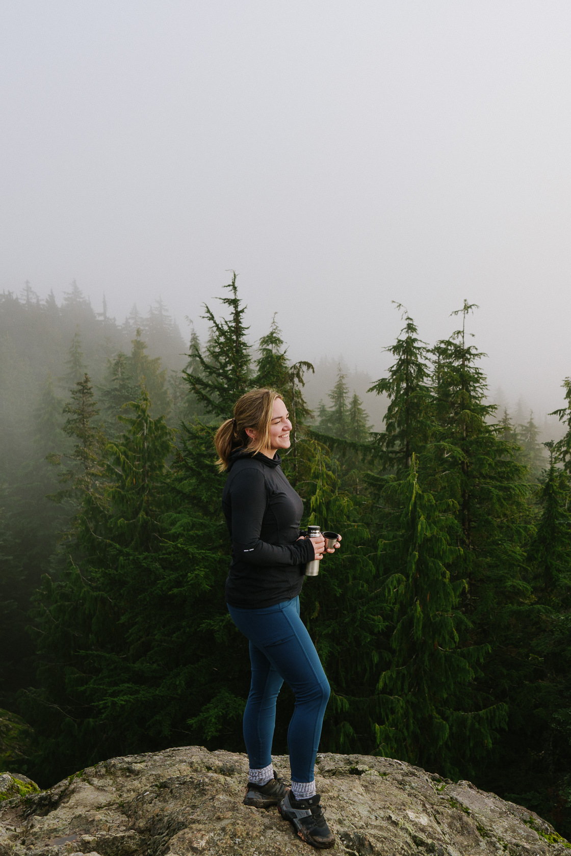 female hiker holding thermos with tea on a cloudy day