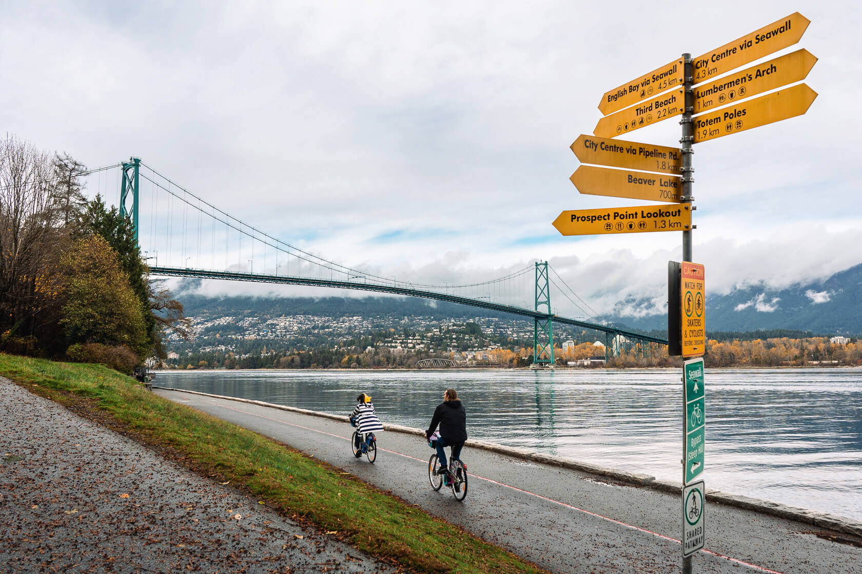 cyclists on Stanley Park seawall by the Lions Gate Bridge