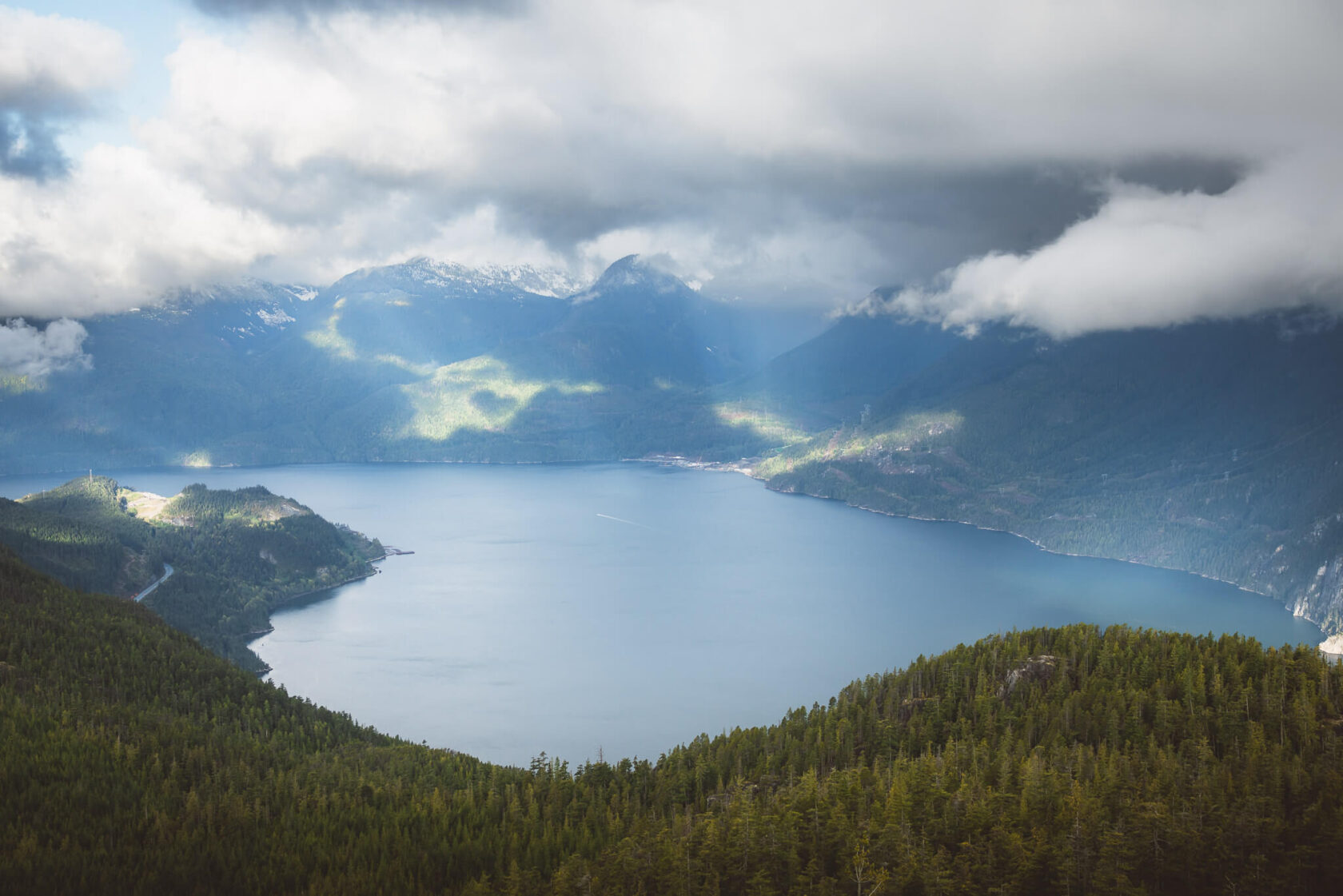 view towards Howe Sound from the Sea to Sky Gondola showing the water and mountains on a cloudy day