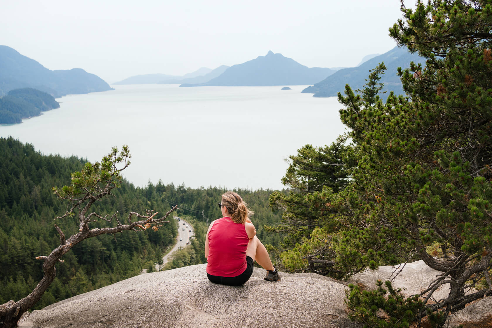 female hiker sitting on the rock looking at Howe Sound from Quercus Point