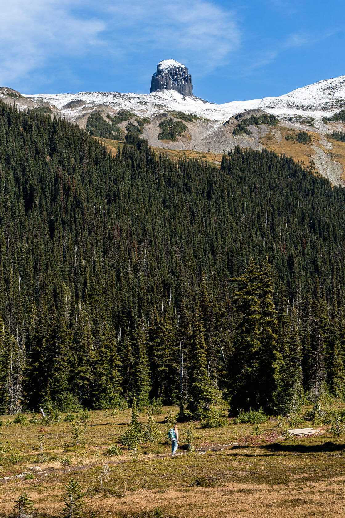 small hiker for scale looking towards Black Tusk chimney from the path leading through Black Tusk meadows